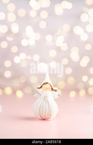 In prossimità dei piccoli piuttosto Angelo vestiti in bianco inverno panno, cartolina natale concetto, femminile sfondo rosa, copyspace Foto Stock