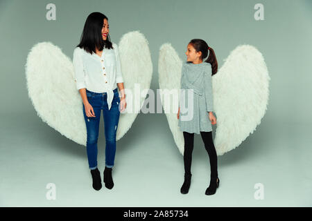 Felice madre e figlia indossando ali d'angelo Foto Stock