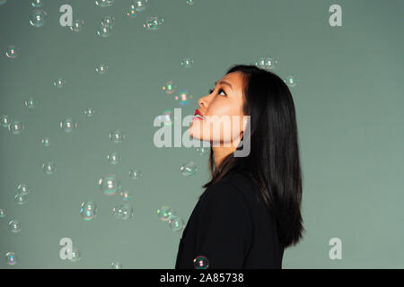 Curioso, fantasiosa giovane donna guardando la caduta di bolle Foto Stock