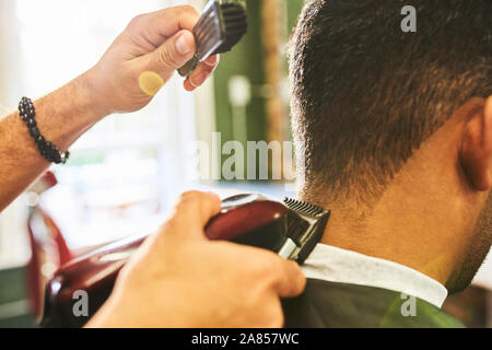 Close up barbiere maschio utilizzando trimmer sui capelli del cliente Foto Stock
