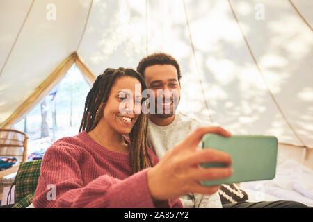 Coppia felice tenendo selfie in camping yurt Foto Stock