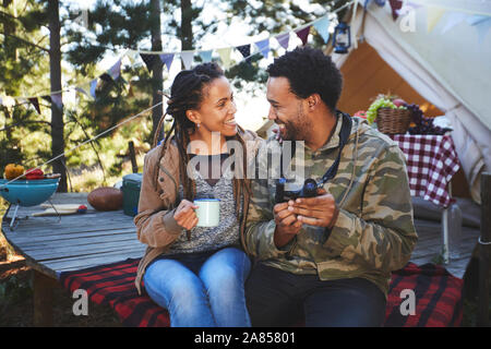 Affettuosa coppia giovane con il binocolo di bere il caffè al campeggio Foto Stock