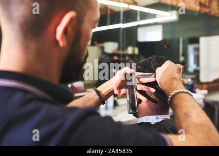 Barbiere di sesso maschile che dà al cliente un taglio di capelli in Barberia Foto Stock