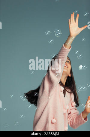 Felice, ragazza spensierate giocando, raggiungendo per la presenza di bolle d'aria Foto Stock