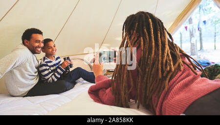 Donna con la fotocamera del telefono a fotografare il marito e il figlio in camping yurt Foto Stock