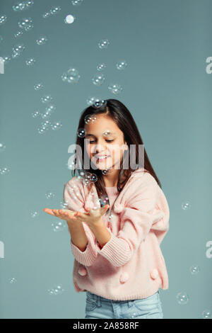 Giocoso ragazza cattura bolle di caduta Foto Stock