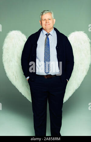 Ritratto di imprenditore sorridente indossando ali d'angelo Foto Stock