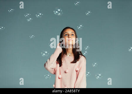 Curioso ragazza guarda la caduta delle bolle Foto Stock