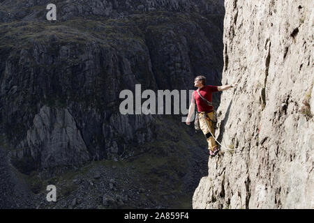 Maschio di scalatore alto di Scala di roccia, guardando a vista sulla spalla Foto Stock