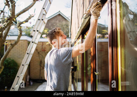 Pittore maschio pittura home esterno del rivestimento del vetro Foto Stock