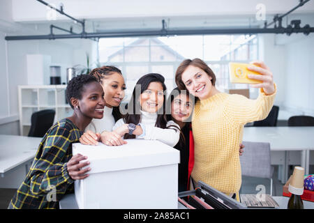 Imprenditrici lo spostamento in nuovi uffici, tenendo selfie Foto Stock