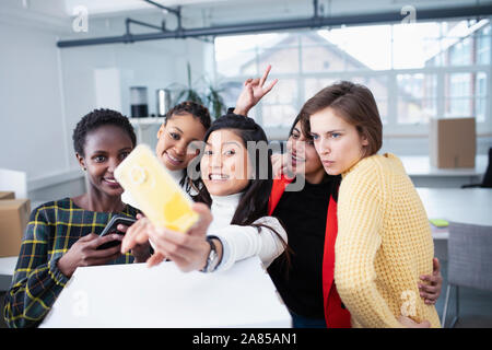 Felice imprenditrici lo spostamento in nuovi uffici, tenendo selfie Foto Stock