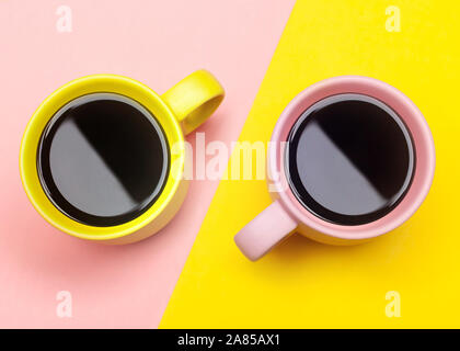 Lay piatto vista dall'alto di due tazze da caffè con rosa e giallo. Foto Stock