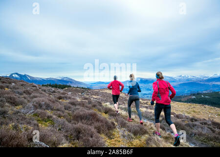 Amici jogging lungo remote mountain trail, Lake District, REGNO UNITO Foto Stock