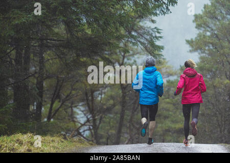 Paio di jogging sul sentiero nel bosco di pioggia Foto Stock