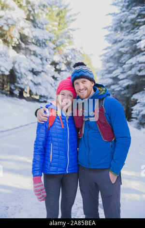 Ritratto felice coppia trekking sul Sentiero nel bosco innevato Foto Stock