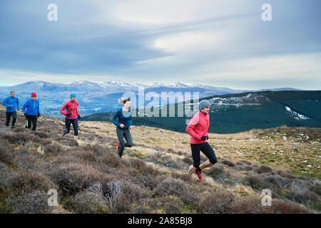 Gli amici di jogging sul sentiero in remoto paesaggio di montagna, Lake District, REGNO UNITO Foto Stock