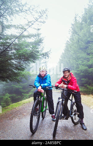 Ritratto di padre e figlio in mountain bike sul sentiero nel bosco di pioggia Foto Stock