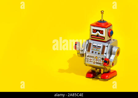 Antico giocattolo di stagno robot su sfondo giallo. Vintage e concetto classico copia libera spazio per il testo. Foto Stock