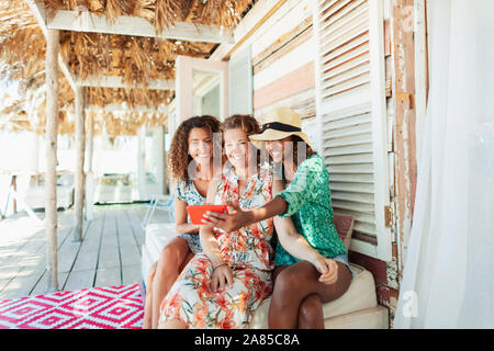 Felice madre e due figlie tenendo selfie su beach hut patio Foto Stock