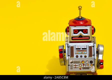 Antico giocattolo di stagno robot su sfondo giallo. Vintage e concetto classico copia libera spazio per il testo. Foto Stock