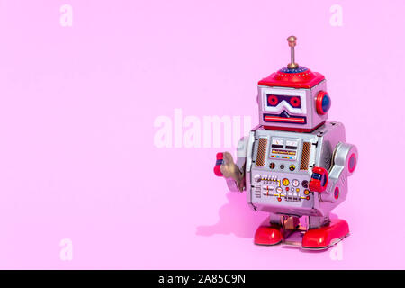 Antico giocattolo di stagno robot su sfondo rosa. Vintage e concetto classico copia libera spazio per il testo. Foto Stock