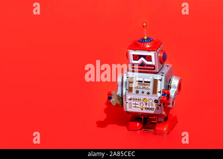 Antico giocattolo di stagno robot su sfondo rosso. Vintage e concetto classico copia libera spazio per il testo. Foto Stock