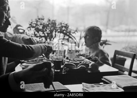 Ein kleiner Junge mit seinen Eltern un einem Tisch in einem Ristorante a Berlino, Deutschland 1970. Un piccolo ragazzo e i suoi genitori la seduta e di pranzare in un ristorante di Berlino in Germania 1970. Foto Stock