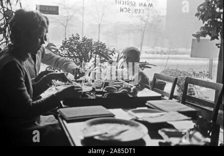 Ein kleiner Junge mit seinen Eltern un einem Tisch in einem Ristorante a Berlino, Deutschland 1970. Un piccolo ragazzo e i suoi genitori la seduta e di pranzare in un ristorante di Berlino in Germania 1970. Foto Stock