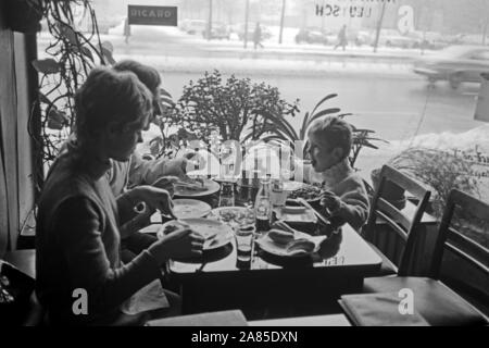 Ein kleiner Junge mit seinen Eltern un einem Tisch in einem Ristorante a Berlino, Deutschland 1970. Un piccolo ragazzo e i suoi genitori la seduta e di pranzare in un ristorante di Berlino in Germania 1970. Foto Stock