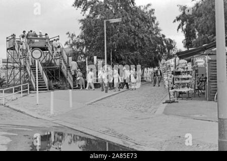 Andenkenläden und Erfrischungsstände machen das grosse Geschäft mit Touristen, die von der Aussichtsplattform am Potsdamer Platz di Berlino einen Blick in den Ostteil der Stadt werfen, Deutschland 1984. Negozi di souvenir e chioschi bisogno di denaro dai turisti che hanno un look da una piattaforma di osservazione a est di Berlino, Germania 1984. Foto Stock