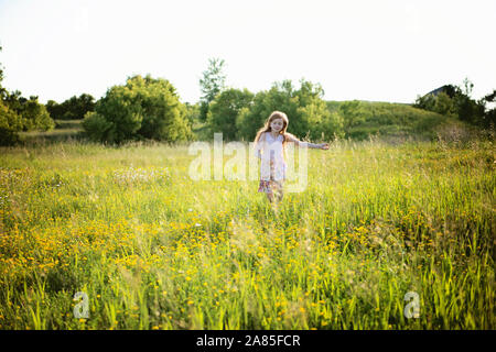 Ragazza con i capelli rossi in abito rosa saltando Prato Foto Stock