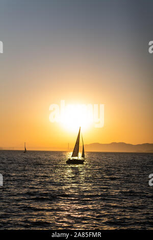 In barca a vela sulla baia di San Francisco al tramonto con il Golden Gate bridge Foto Stock