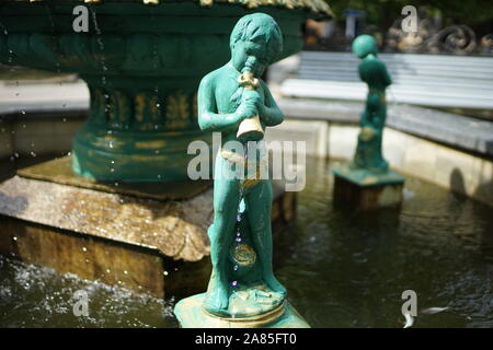 Fontana con ragazzi che versa acqua dalla nave. Cupido statua. Foto Stock