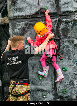 Soldato dell'esercito aiuta un giovane bambino salire su di una parete da arrampicata, airshow nazionale, East Fortune, East Lothian, Scozia, Regno Unito Foto Stock