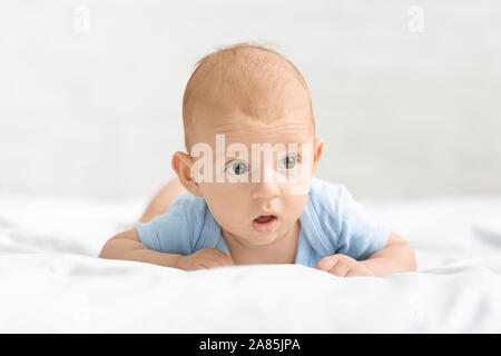 Ritratto di divertenti neonato sdraiato sulla pancia a letto Foto Stock