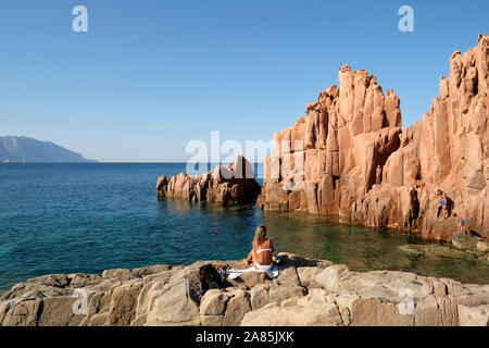 Turisti che si godono la rocce rosse / Porphyry Red Rocks Beach Arbatax, costa Ogliastra a Tortolì, Sardegna, Italia - prendere il sole Foto Stock