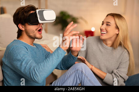 Ragazzo e ragazza utilizzando cuffie VR seduto sul piano piscina Foto Stock