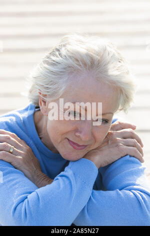 Senior donna seduta su un molo Foto Stock