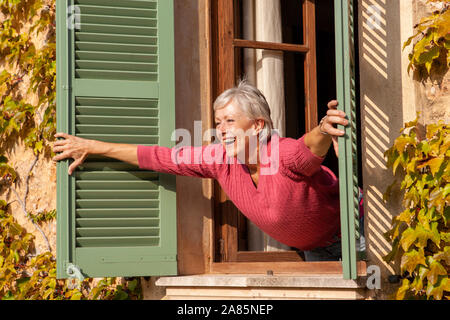 Senior donna l'apertura della finestra Foto Stock