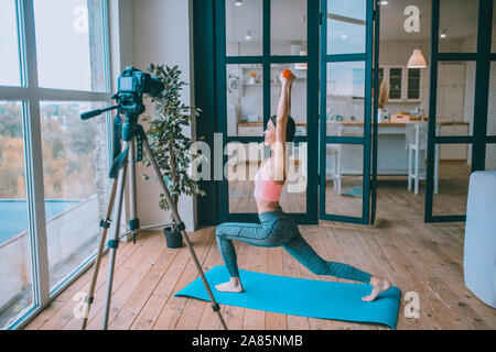 Blogger Fitness facendo esercizi con barbells in mattinata Foto Stock