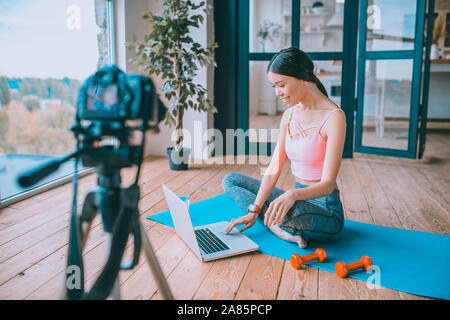 Blogger Fitness utilizzando il proprio portatile mentre si lavora sul nuovo video Foto Stock