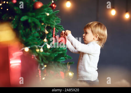 Un ragazzino decora l'albero di Natale Foto Stock