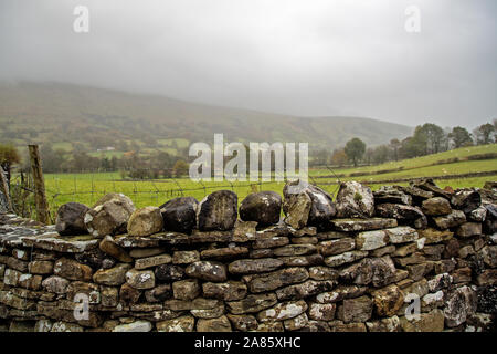 Una casa isolata su una collina distante e oscurata dalle basse nubi a Dent, Dentdale, North Yorkshire National Park, Regno Unito Foto Stock