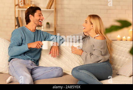 Giovane godendo di conversazione avente il caffè seduti sul divano di casa Foto Stock