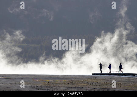 I visitatori si stagliano pennacchi di vapore a Grand Prismatic Hot Springs nel Parco Nazionale di Yellowstone, Wyoming USA Foto Stock