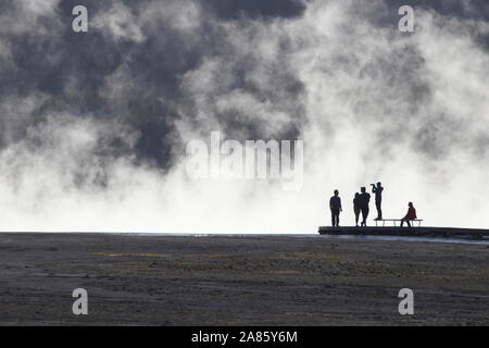 I visitatori si stagliano pennacchi di vapore a Grand Prismatic Hot Springs nel Parco Nazionale di Yellowstone, Wyoming USA Foto Stock