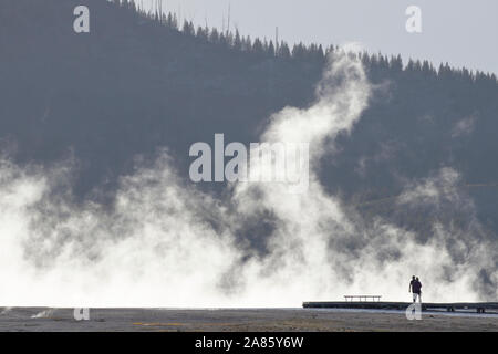 I visitatori si stagliano pennacchi di vapore a Grand Prismatic Hot Springs nel Parco Nazionale di Yellowstone, Wyoming USA Foto Stock