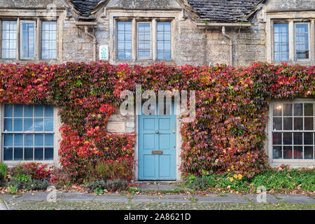 Parthenocissus tricuspidata. Boston Ivy / superriduttore giapponesi in autunno su un cotswold cottage in pietra a Burford, Cotswolds, Oxfordshire, Inghilterra Foto Stock