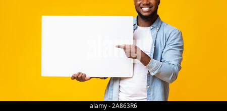 Uomo nero azienda bianco pubblicità board e puntando su di esso Foto Stock